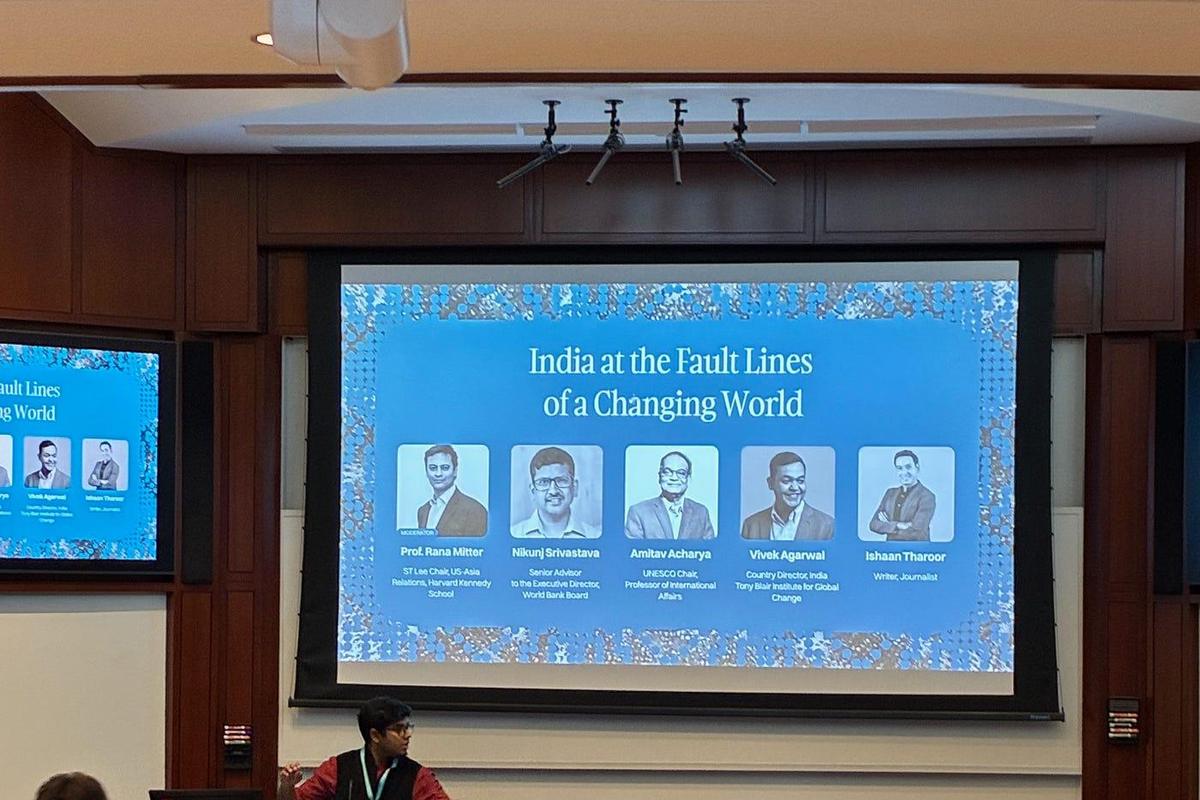Panellists at a long table beneath a screen showing the session title