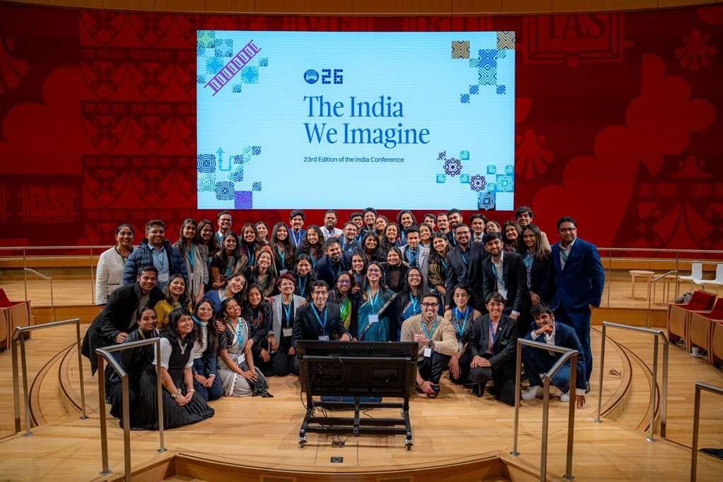 A large group gathered on stage beneath a screen reading The India We Imagine